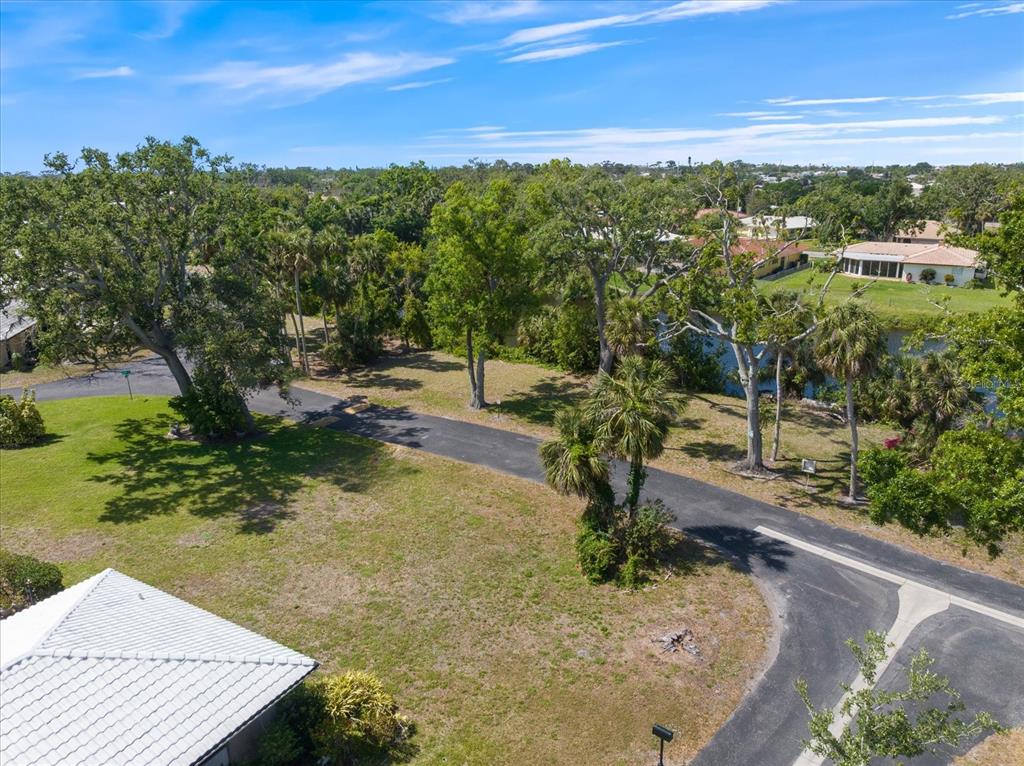 An aerial view shows a vacant grassy lot with mature trees and a paved road — 531 VILLA PARK DRIVE UNIT 531, NOKOMIS, FL