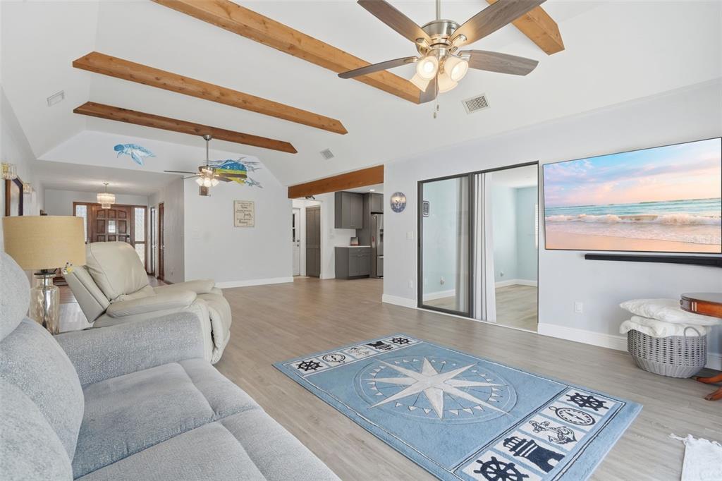 A living room features vaulted ceilings with exposed wooden beams, light flooring, and a nautical rug — 82 JENNIFER CIRCLE, PONCE INLET, FL