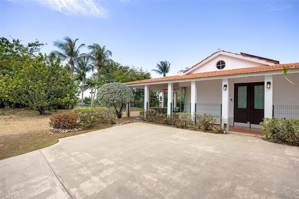 A concrete driveway leads to the covered porch and entrance of a white house — 134 CAMINO DE LA CANA, DORADO, PR