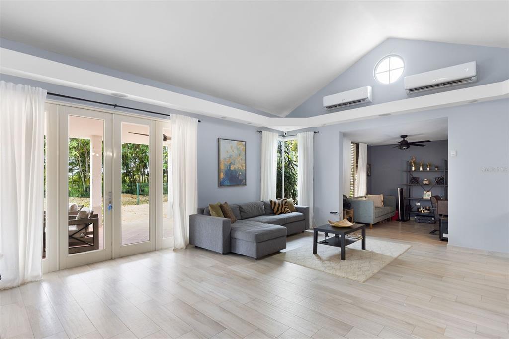 A living room with light wood floors, a grey sectional sofa, and vaulted ceilings — 134 CAMINO DE LA CANA, DORADO, PR