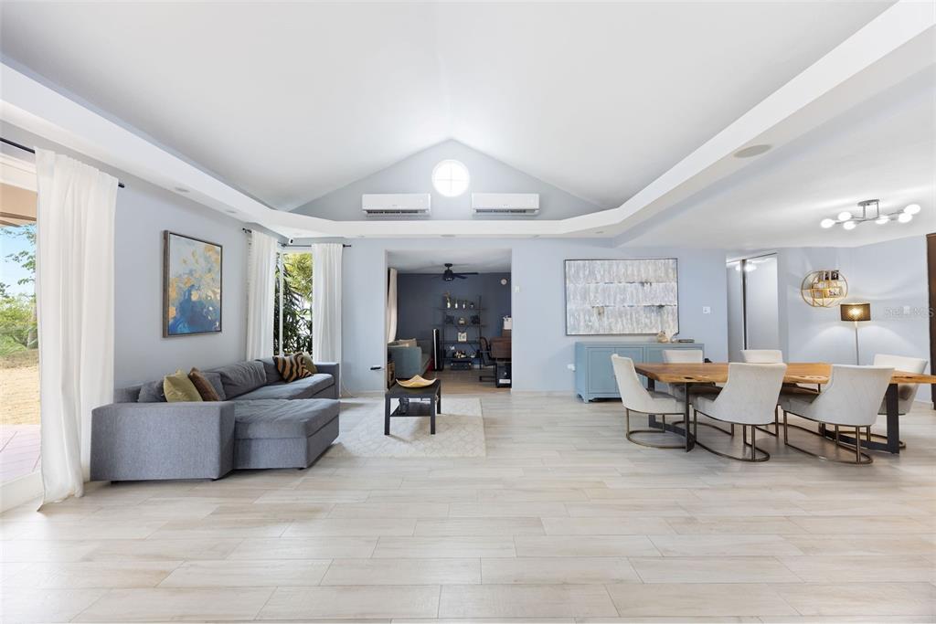 A spacious open-concept living and dining area features vaulted ceilings, light wood-look flooring, and neutral walls — 134 CAMINO DE LA CANA, DORADO, PR