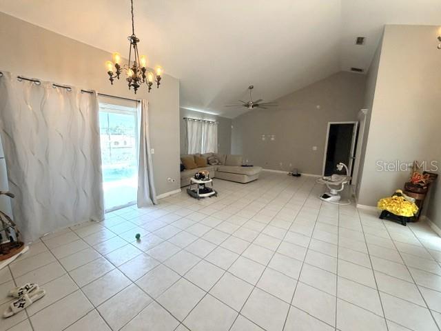 A spacious living room features light-colored tile flooring, a vaulted ceiling, and a chandelier — 1677 SACKETT CIRCLE, ORLANDO, FL