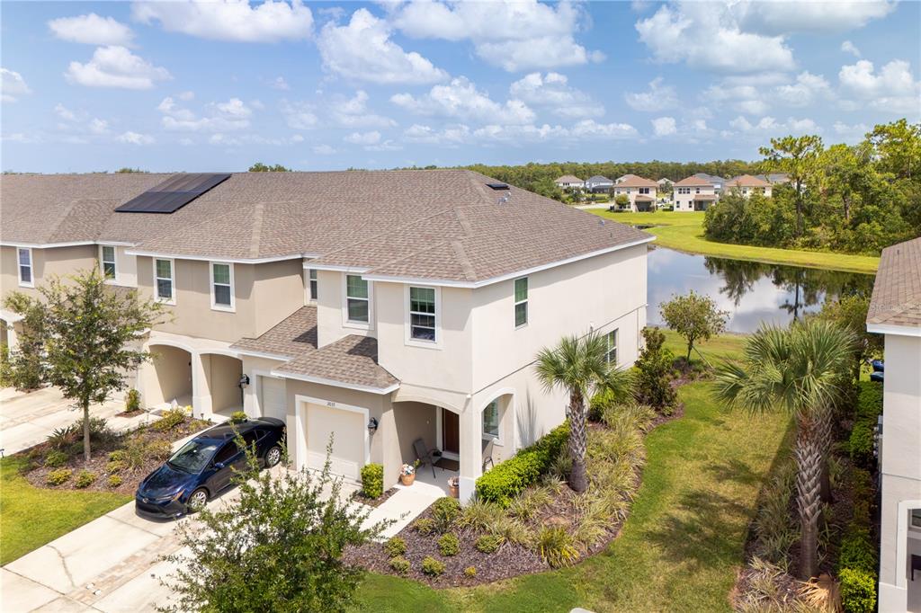 An aerial view of a two-story townhouse with a garage, driveway, and a backyard pond — 2037 CRYSTAL BELL STREET, ORLANDO, FL
