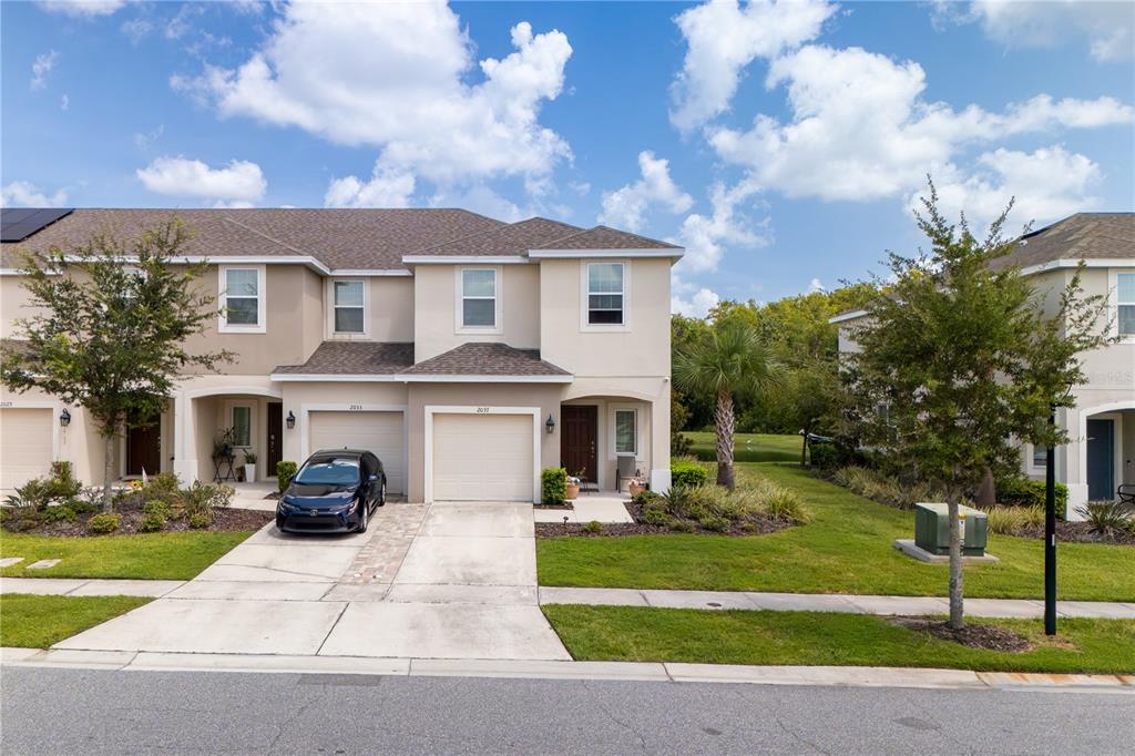 A two-story townhouse with a beige exterior, a two-car garage, and a paved driveway — 2037 CRYSTAL BELL STREET, ORLANDO, FL