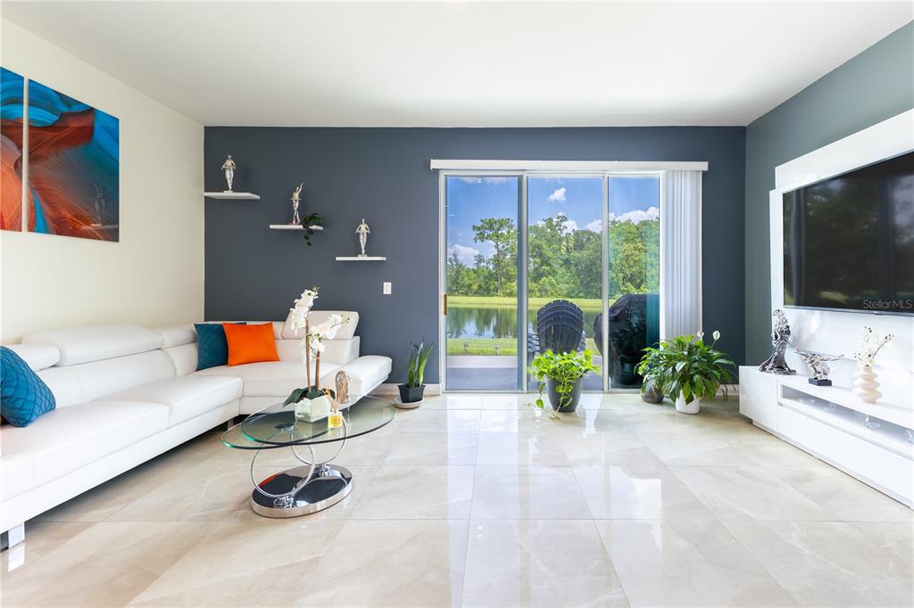 A modern living room features white tile floors, a white sectional sofa, and sliding glass doors — 2037 CRYSTAL BELL STREET, ORLANDO, FL