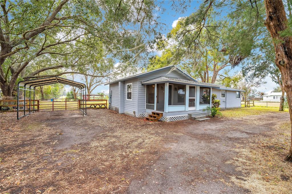 A light blue single-story house with a metal carport and a screened-in front porch — 13713 WALDEN SHEFFIELD ROAD, DOVER, FL