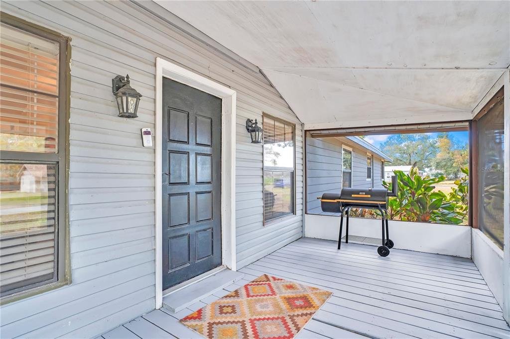 A covered porch with gray siding, a dark front door, and a charcoal grill — 13713 WALDEN SHEFFIELD ROAD, DOVER, FL