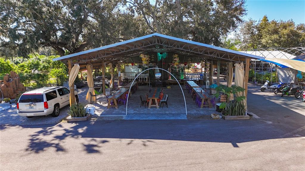 An outdoor covered pavilion features long wooden tables, chairs, and a paved floor — 21552 E STATE ROAD 64, BRADENTON, FL