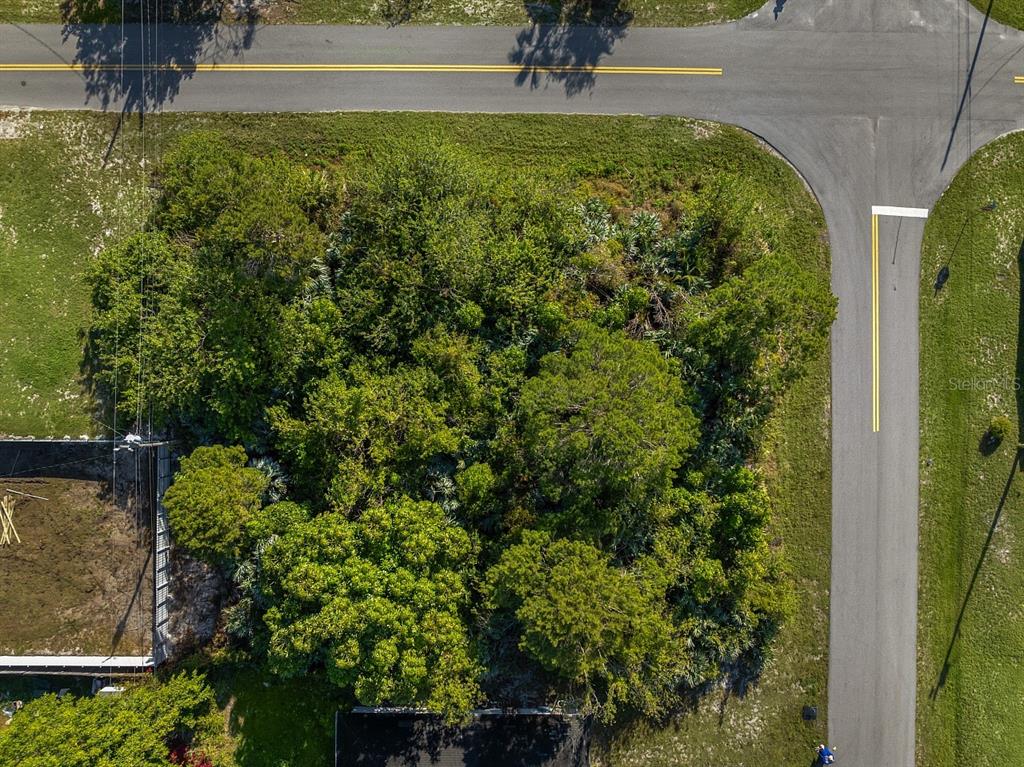 An aerial view shows a wooded, undeveloped corner lot situated between two paved roads — 1505 4TH AVENUE SW, VERO BEACH, FL