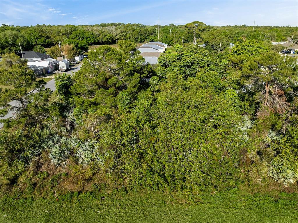 An aerial view shows a dense, wooded lot bordered by a grassy area and nearby houses — 1505 4TH AVENUE SW, VERO BEACH, FL