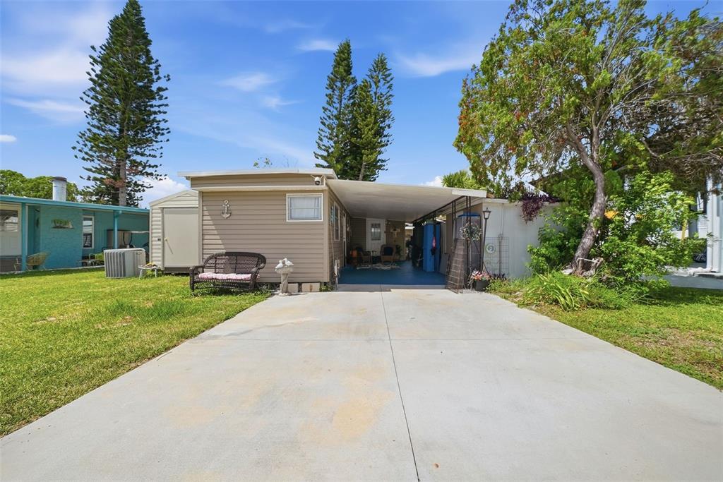 A beige mobile home with a concrete driveway, carport, and a small storage shed — 6439 TOWER DRIVE, HUDSON, FL