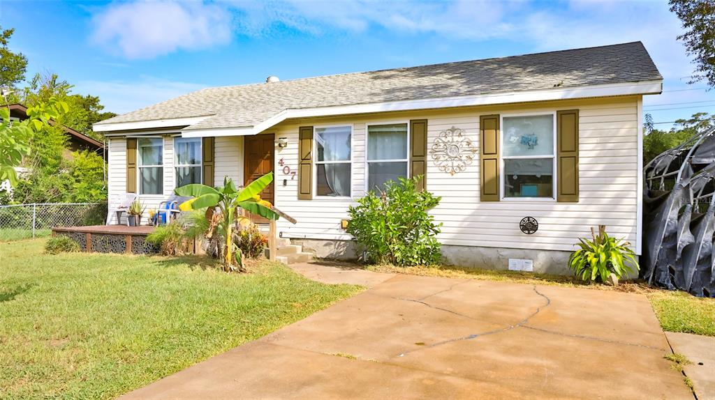 A single-story house with light-colored siding, a concrete driveway, and a small front porch — 407 ANN STREET, EDGEWATER, FL