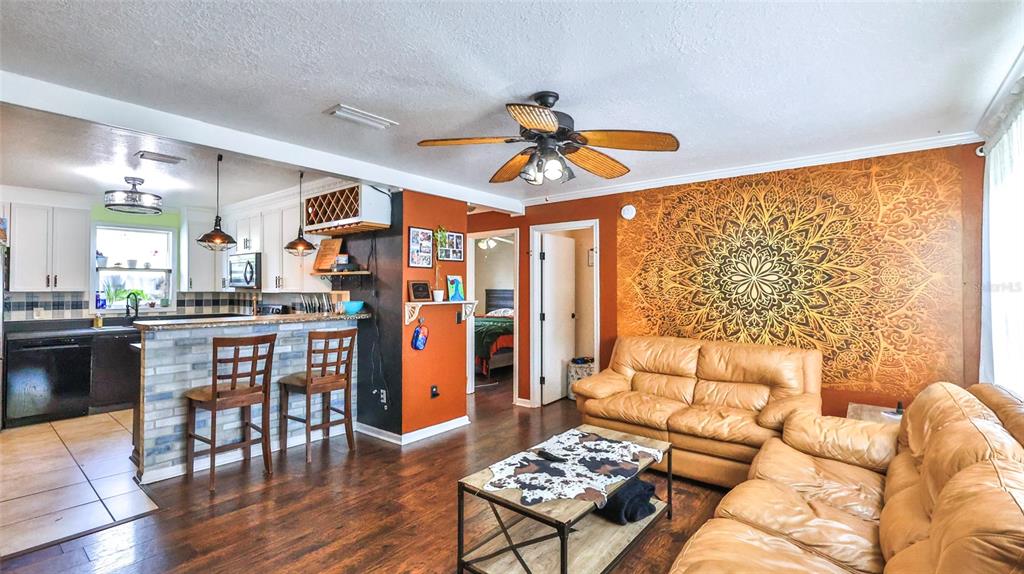 An open-concept living room and kitchen feature a large mandala wall mural and leather sofas — 407 ANN STREET, EDGEWATER, FL