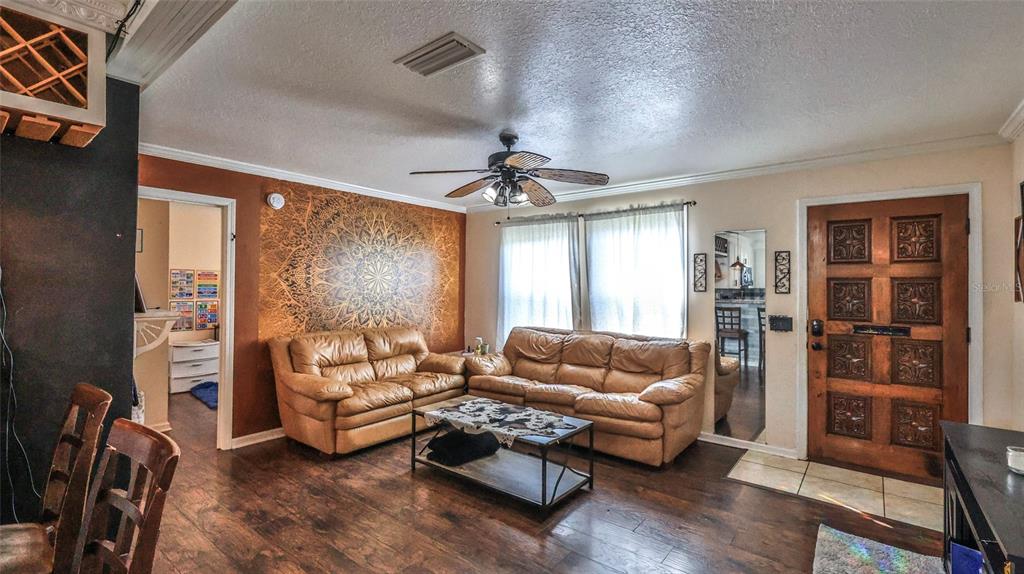 A living room features two leather sofas, a mandala wall mural, and a wooden door — 407 ANN STREET, EDGEWATER, FL