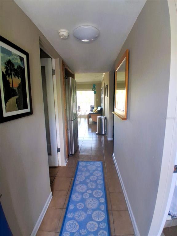 A hallway with tile floors, a blue patterned runner rug, and a stainless steel refrigerator — 2850 GULF OF MEXICO DRIVE UNIT 2, LONGBOAT KEY, FL