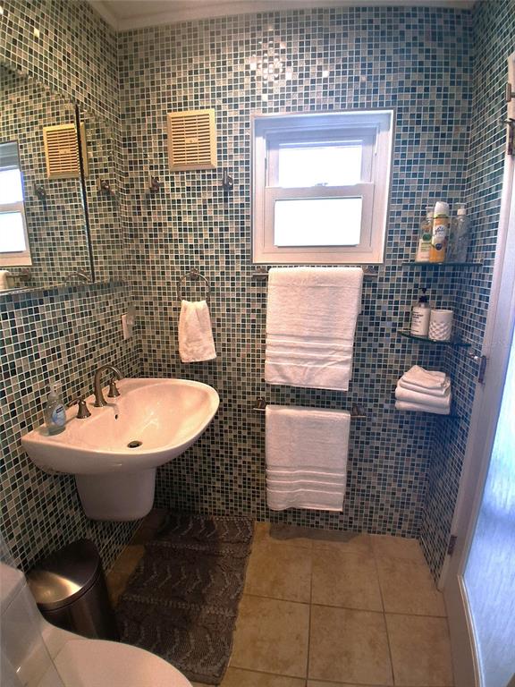 A bathroom features a pedestal sink, a window, and walls covered in small green mosaic tiles — 2850 GULF OF MEXICO DRIVE UNIT 2, LONGBOAT KEY, FL