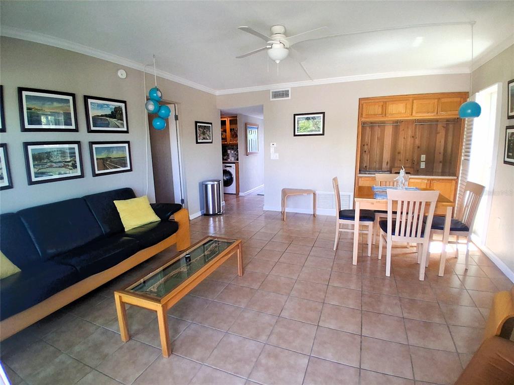 A living and dining area with tile floors, a black sofa, and wooden cabinets — 2850 GULF OF MEXICO DRIVE UNIT 2, LONGBOAT KEY, FL