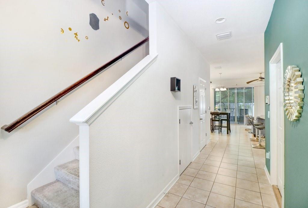 A hallway with tiled floors leads to a dining area past a staircase with carpet — 6982 HOLLY HEATH DRIVE, RIVERVIEW, FL