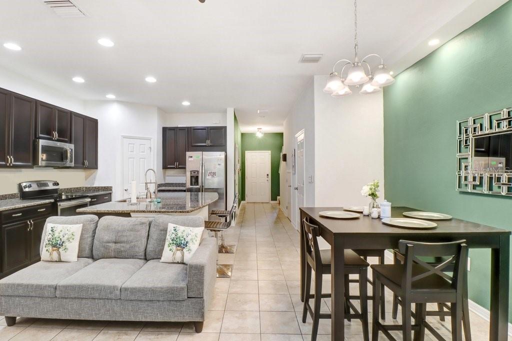 An open-concept kitchen, dining area, and living room with dark cabinetry and green accent walls — 6982 HOLLY HEATH DRIVE, RIVERVIEW, FL
