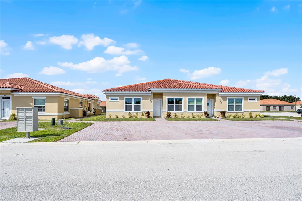 A tan duplex with a red tile roof and a brick paver driveway — 1826 CORIANDER DRIVE, KISSIMMEE, FL