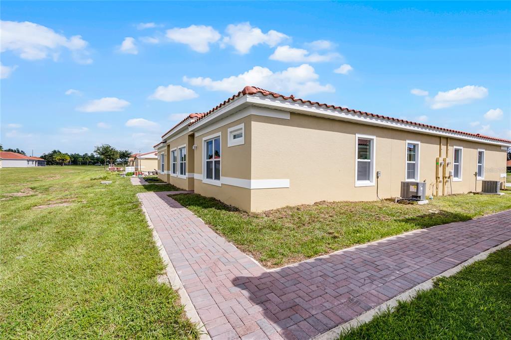 A tan stucco house exterior with a red tile roof and a brick paver walkway — 1826 CORIANDER DRIVE, KISSIMMEE, FL