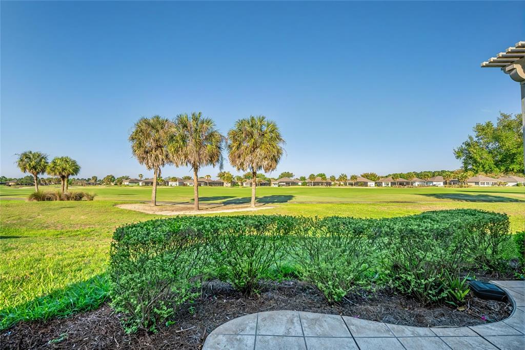 A view from a tiled patio overlooking a grassy golf course with palm trees — 9565 SW 70TH LOOP, OCALA, FL