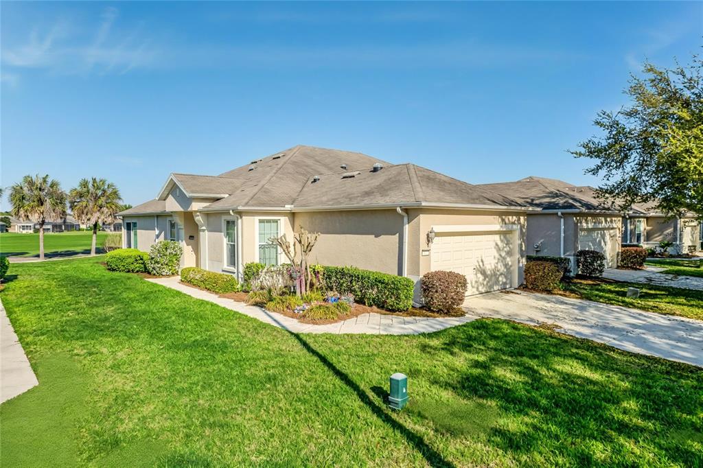 A tan, single-story house with a two-car garage and a landscaped front yard — 9565 SW 70TH LOOP, OCALA, FL