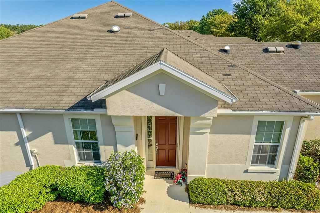 An exterior view of a house entrance with a brown door and a shingled roof — 9565 SW 70TH LOOP, OCALA, FL