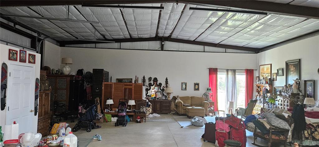 A large, open-concept room with a high metal ceiling, concrete floors, and varied furniture — 691 S LAKE PATRICK ROAD, FROSTPROOF, FL