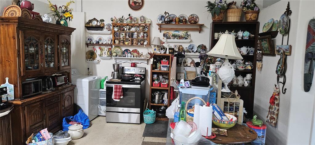 This cluttered kitchen features a wooden hutch, a stainless steel stove, and numerous decorative plates — 691 S LAKE PATRICK ROAD, FROSTPROOF, FL