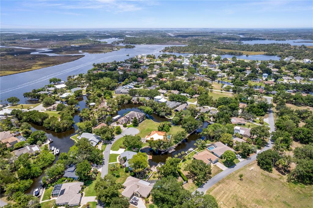 An aerial view shows houses nestled among trees and canals near a large body of water — 11649 W CLUBVIEW DRIVE, HOMOSASSA, FL