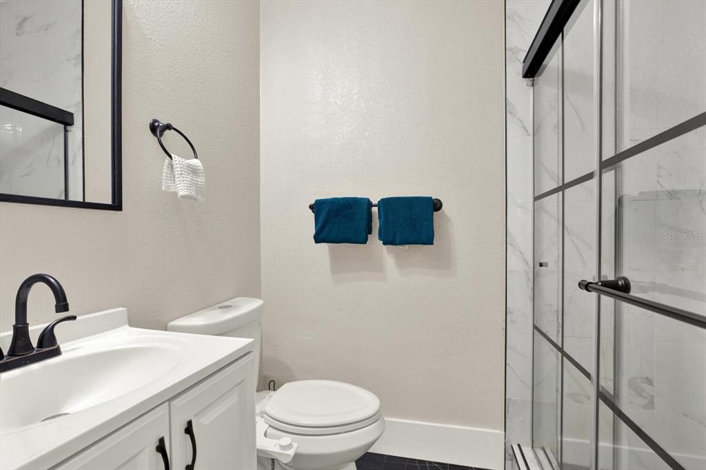 A bathroom features a white vanity, a toilet with a bidet, and a glass-enclosed shower — 1945 OVERBROOK AVENUE, CLEARWATER, FL