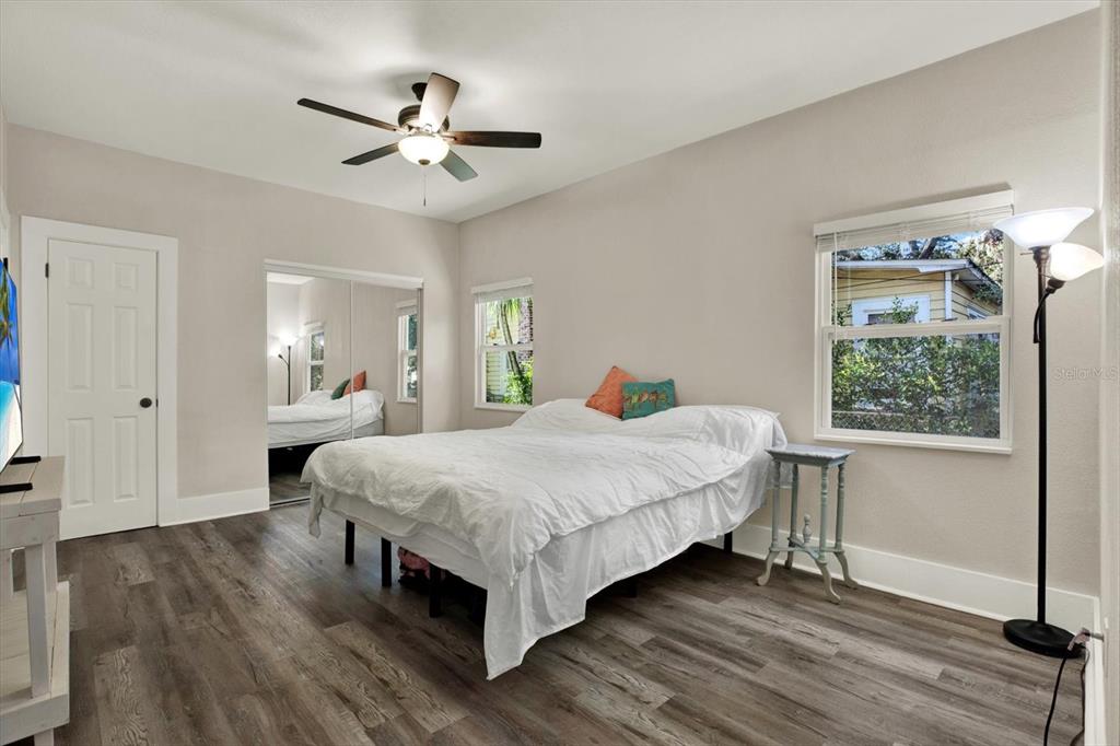 A bedroom features gray wood-look flooring, a ceiling fan, a bed, and a mirrored closet — 1945 OVERBROOK AVENUE, CLEARWATER, FL