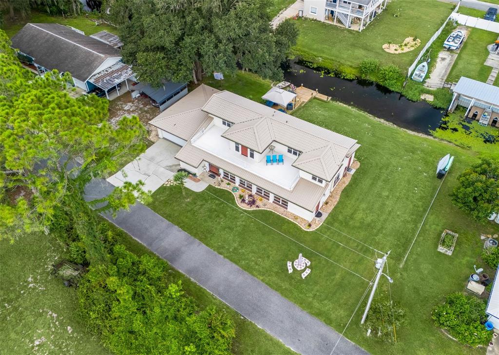 An aerial view of a house with a metal roof, a flat deck, and a canal — 14478 SE 107TH TERRACE, SUMMERFIELD, FL