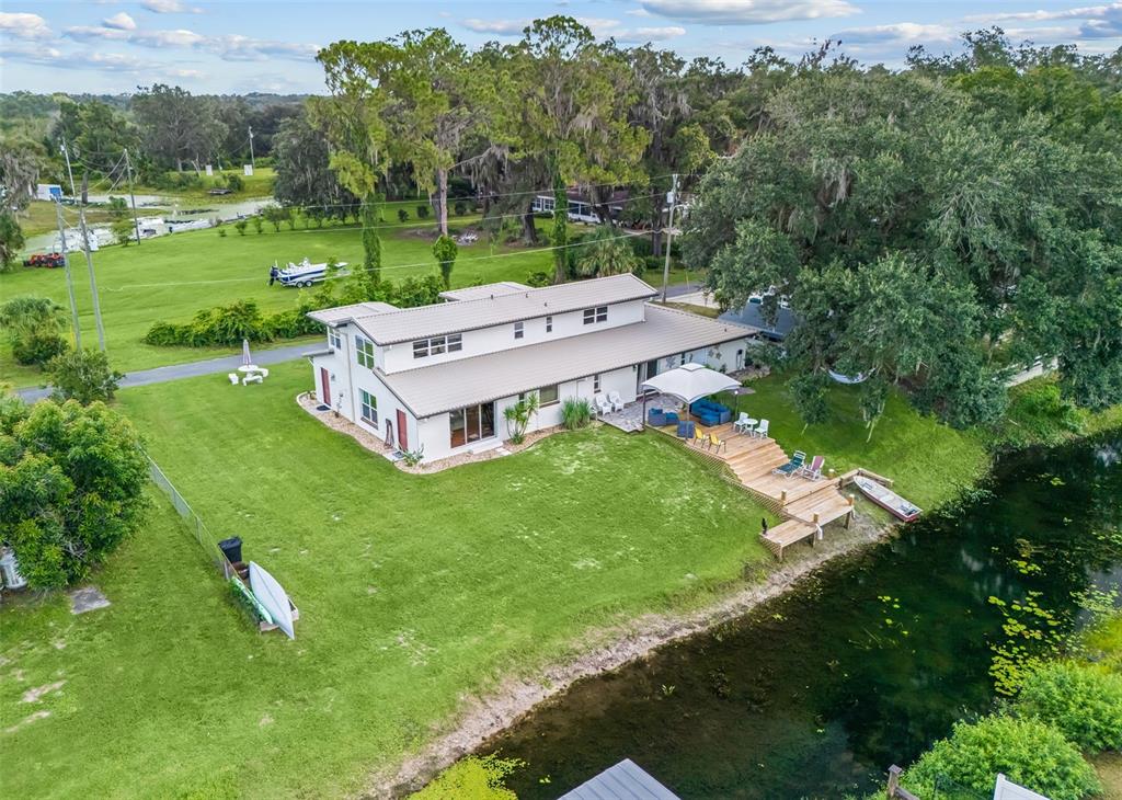 An aerial view shows a two-story house with a wooden deck overlooking a canal — 14478 SE 107TH TERRACE, SUMMERFIELD, FL