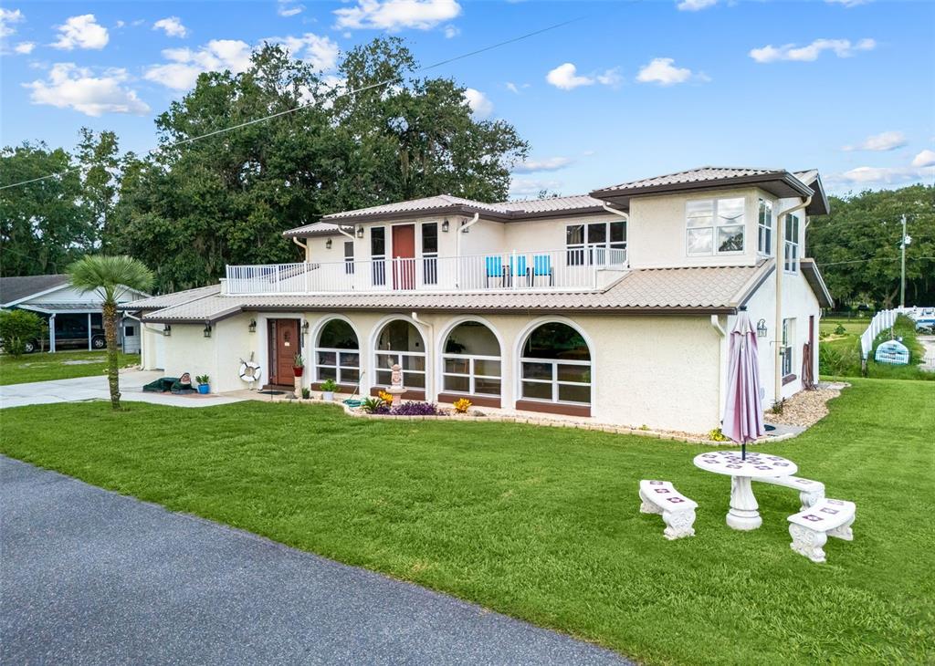 A two-story house with a white stucco exterior, arched windows, and a second-floor balcony — 14478 SE 107TH TERRACE, SUMMERFIELD, FL
