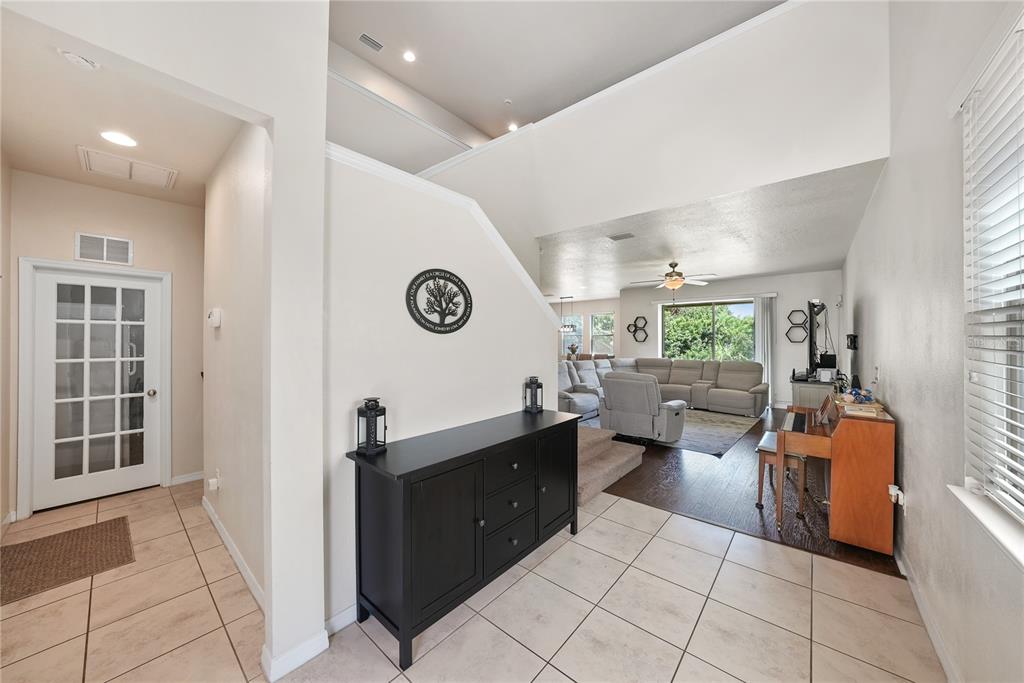 A foyer with tile flooring leads into a living room with wood floors and vaulted ceilings — 8415 LOBLOLLY PINE COURT, RIVERVIEW, FL