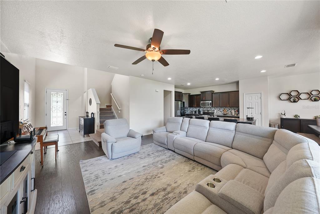 A living room with a large sectional sofa, gray area rug, and open kitchen — 8415 LOBLOLLY PINE COURT, RIVERVIEW, FL
