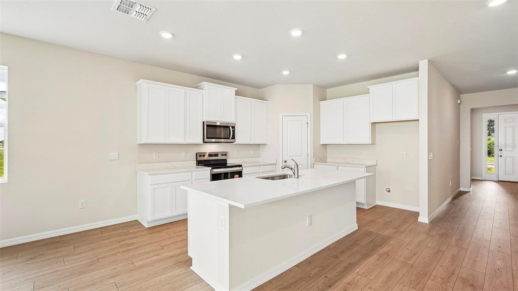 A kitchen with white cabinets, a central island, and light wood-look flooring — 2814 FISHERY COURT, LAKEWOOD RANCH, FL