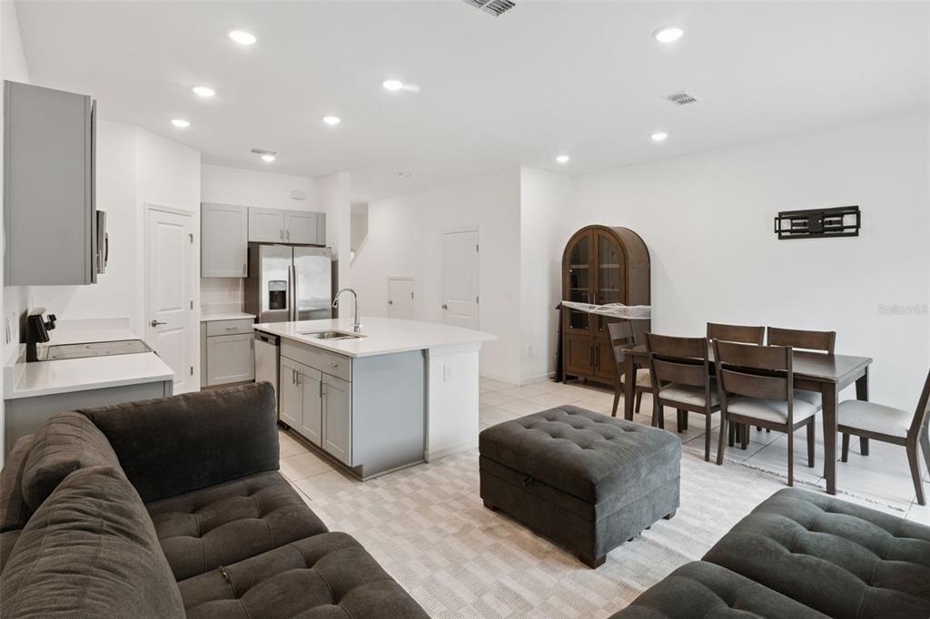 An open-concept kitchen and dining area features gray cabinetry, a central island, and dark furniture — 2251 PORTRAIT STREET, POINCIANA, FL