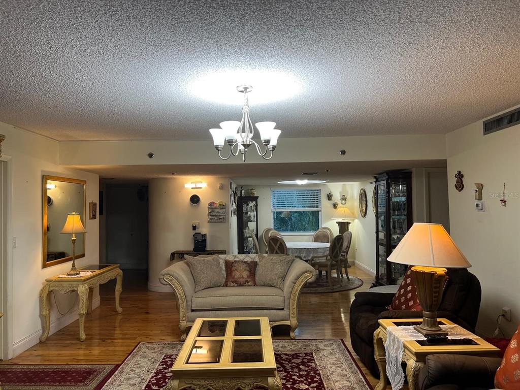 A living room with hardwood floors, a chandelier, a sofa, and a dining area beyond — 3910 INVERRARY BOULEVARD UNIT B301, LAUDERHILL, FL