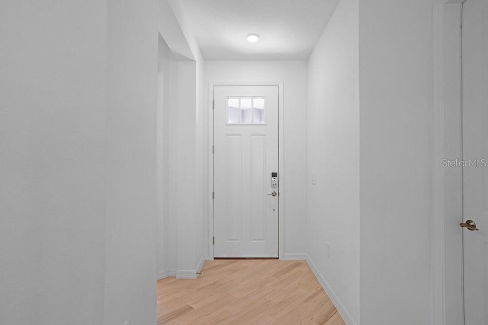 A white front door opens into a small entryway with light wood-look flooring — 735 STEEL DRIVE, APOLLO BEACH, FL