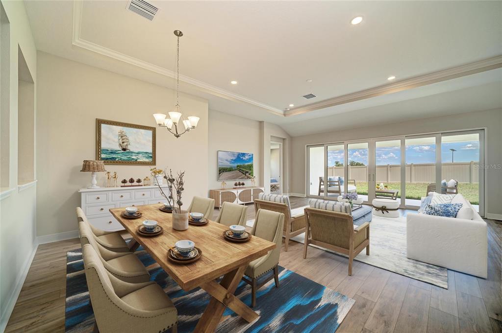 An open-concept living area features wood-look flooring, recessed lighting, and large sliding glass doors — 9806 LEAF GREEN LANE, DADE CITY, FL