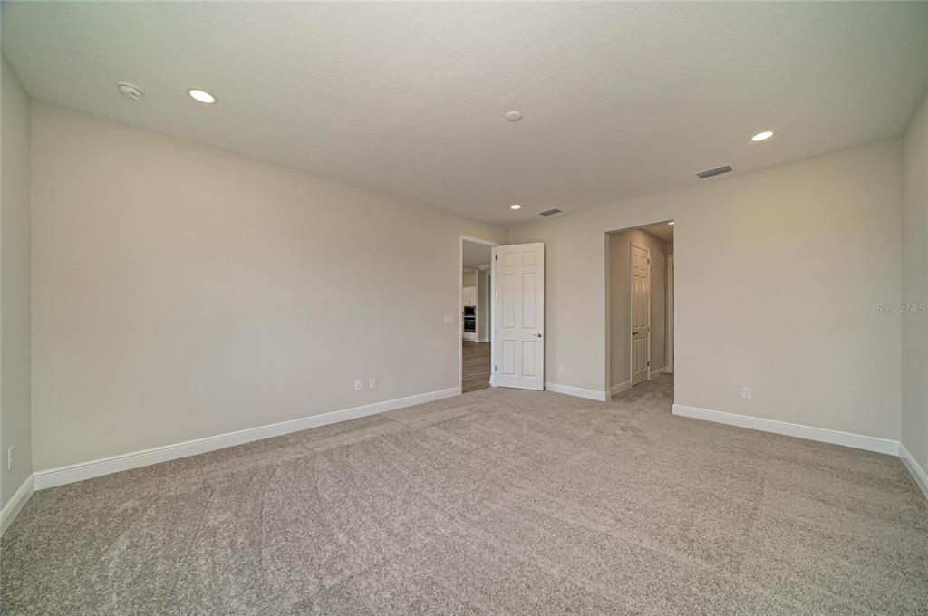 A bathroom features a double vanity with white cabinets, a large mirror, and a glass-enclosed shower — 9806 LEAF GREEN LANE, DADE CITY, FL