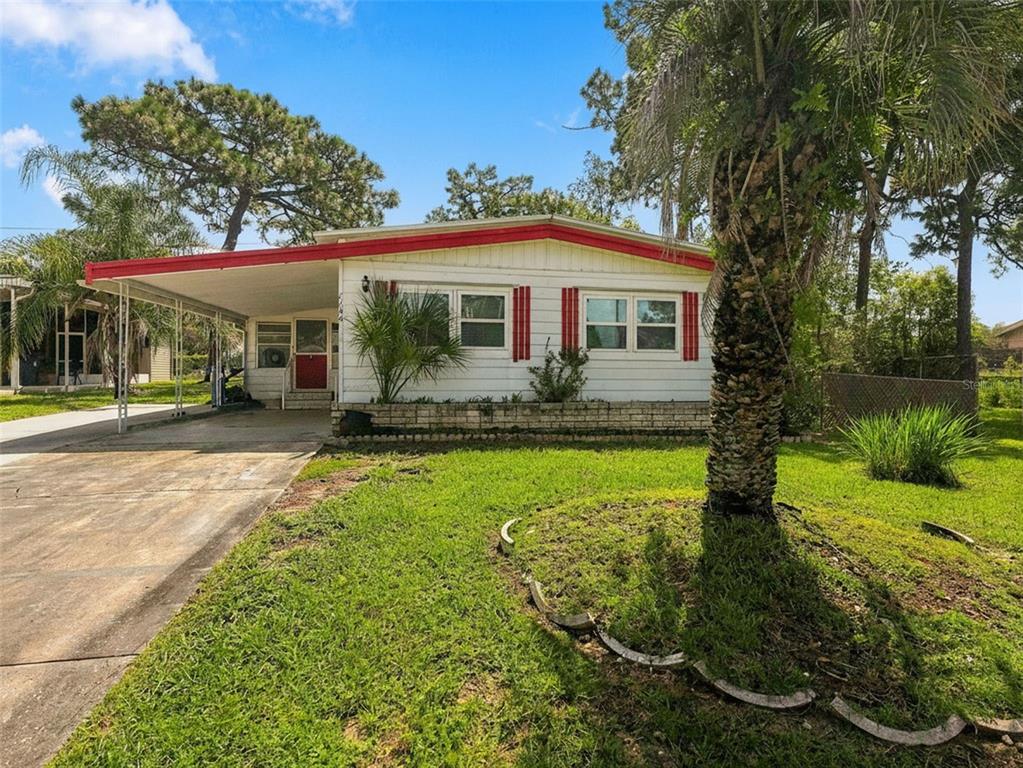 A single-story mobile home with white siding, a red roof trim, and an attached carport — 7156 FITZPATRICK AVENUE, BROOKSVILLE, FL