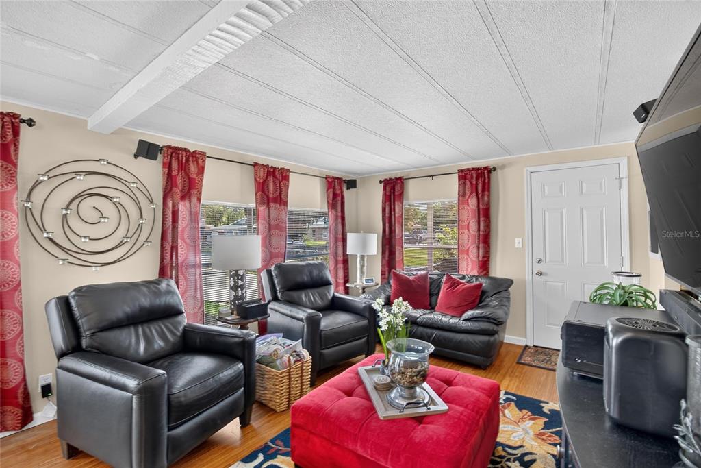 A living room features black leather seating, a red ottoman, and red patterned curtains — 2715 EATON AVENUE, EATON PARK, FL
