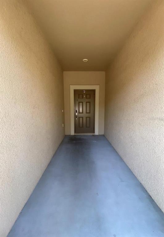 A narrow, covered entryway leads to a brown front door with a light-colored frame — 12013 GREENGATE DRIVE, HUDSON, FL
