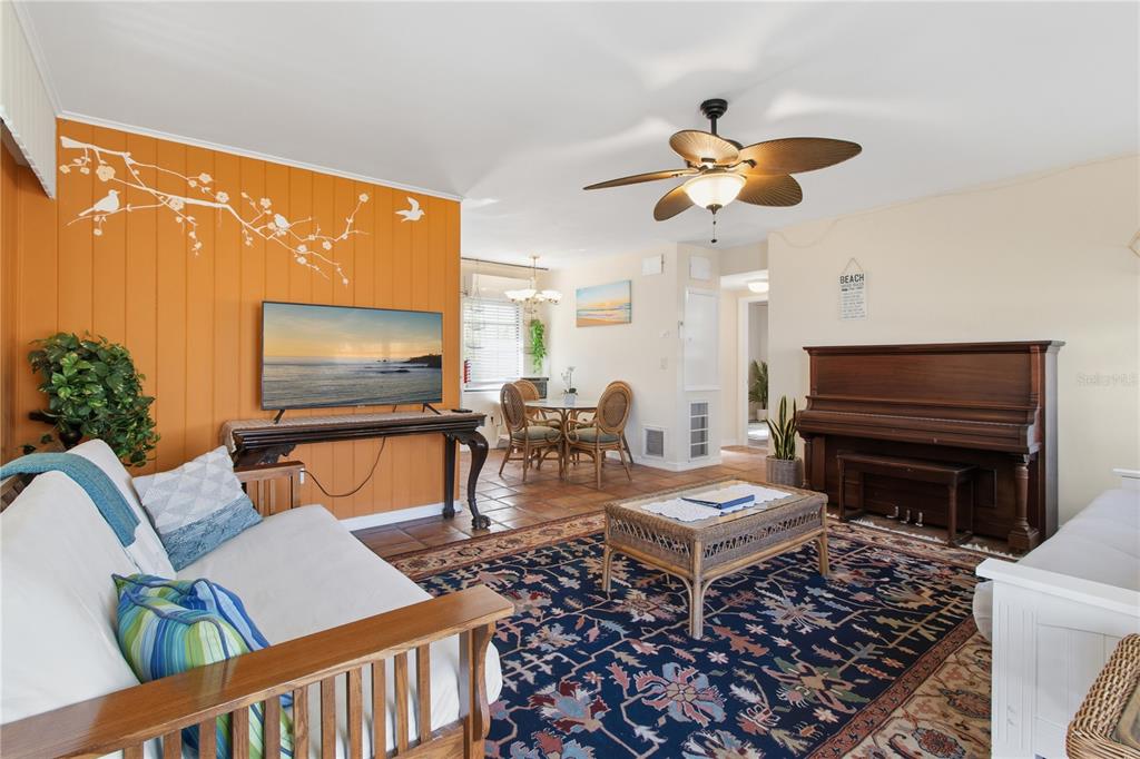 A living room features an orange accent wall, a piano, a ceiling fan, and tile flooring — 311 59TH STREET, HOLMES BEACH, FL