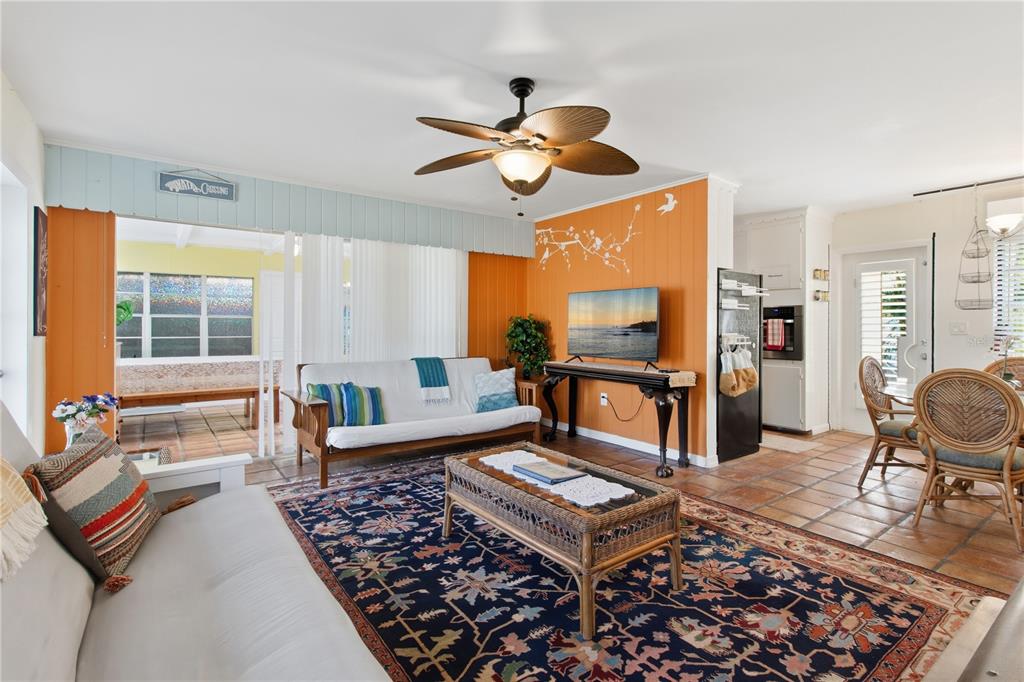 A living room features orange walls, a patterned area rug, and a wicker coffee table — 311 59TH STREET, HOLMES BEACH, FL