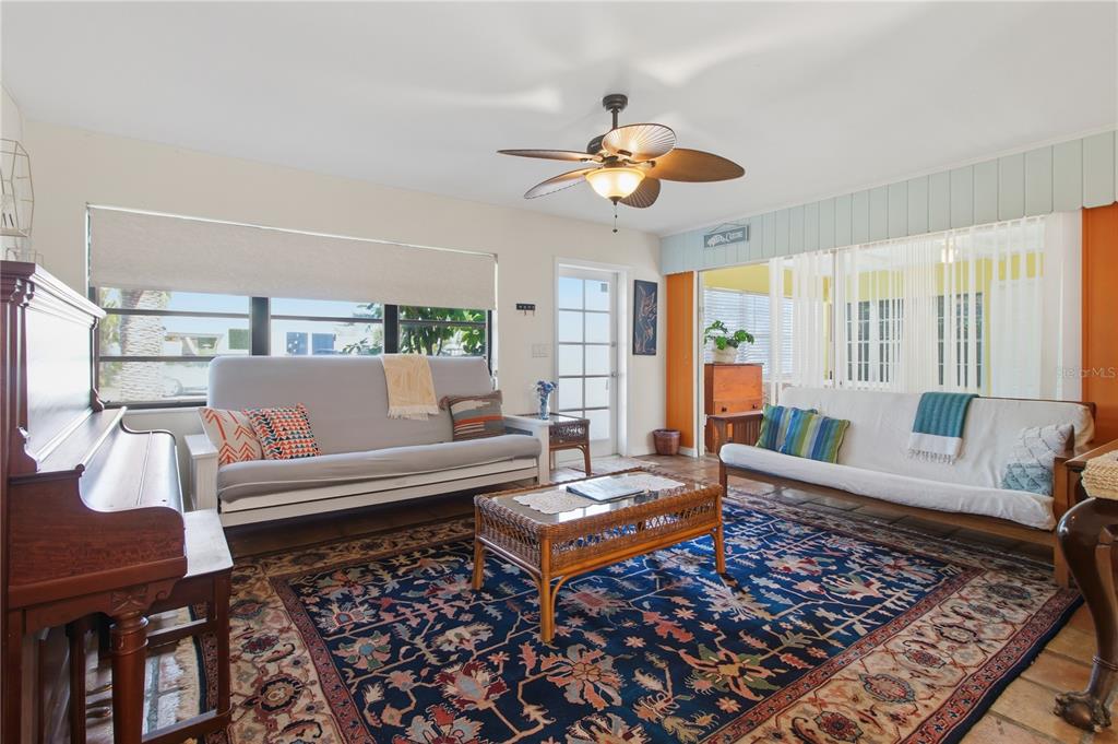 A living room features two futons, a large patterned rug, and a ceiling fan — 311 59TH STREET, HOLMES BEACH, FL